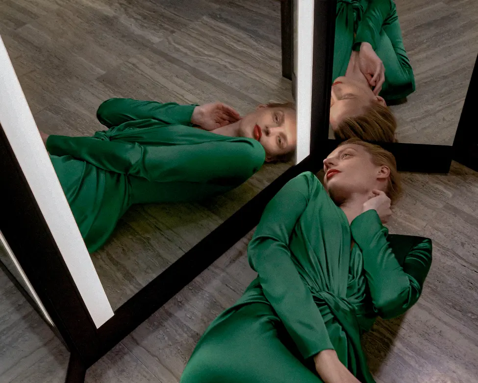 woman laying on floor in front of triptych mirror