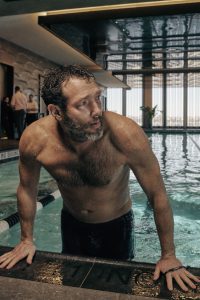 man getting out of indoor pool at fitness club