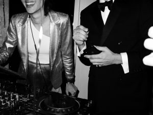 female dj smiling with man in tuxedo at party