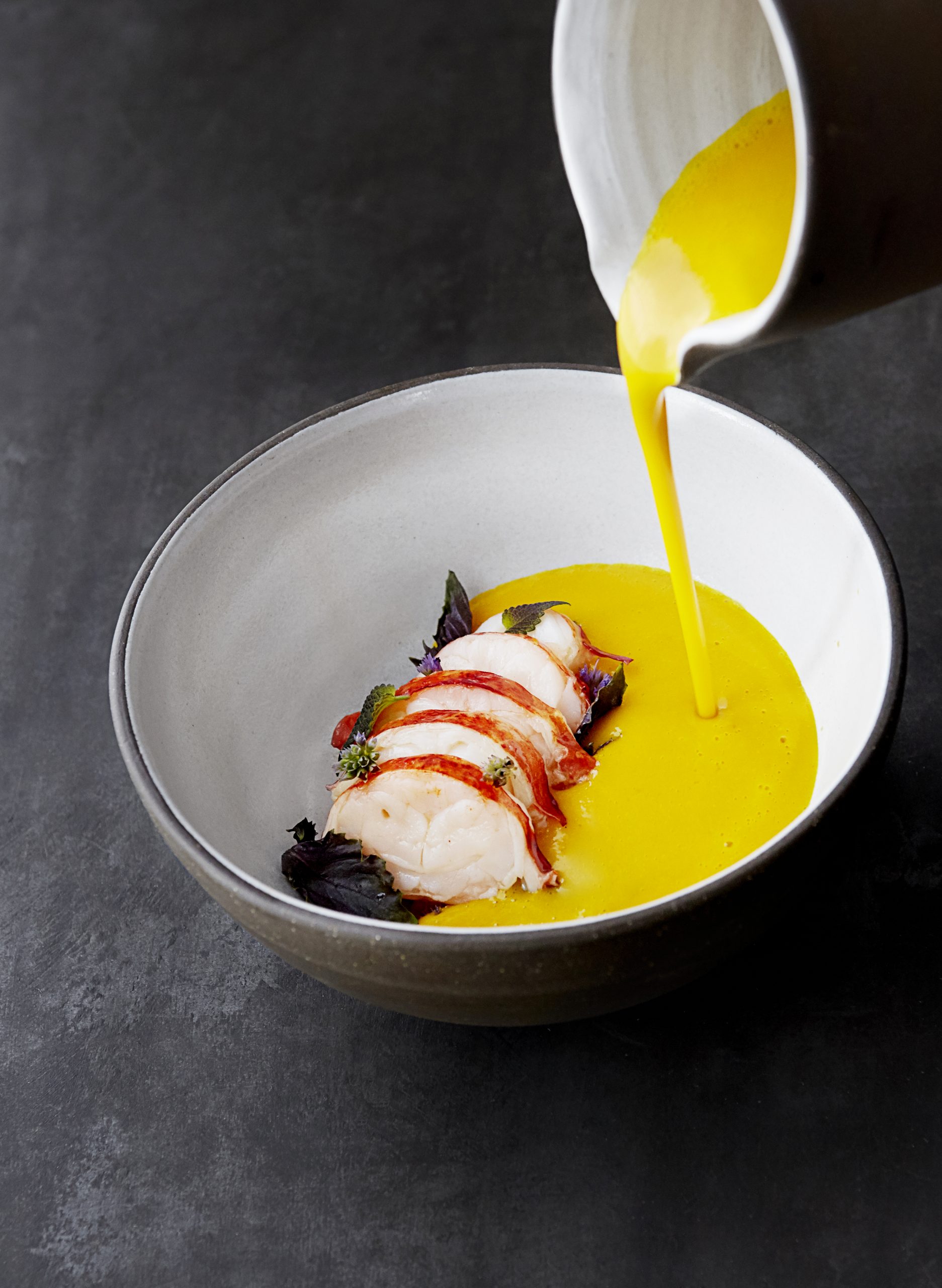 pumpkin soup being poured into bowl of poached lobster