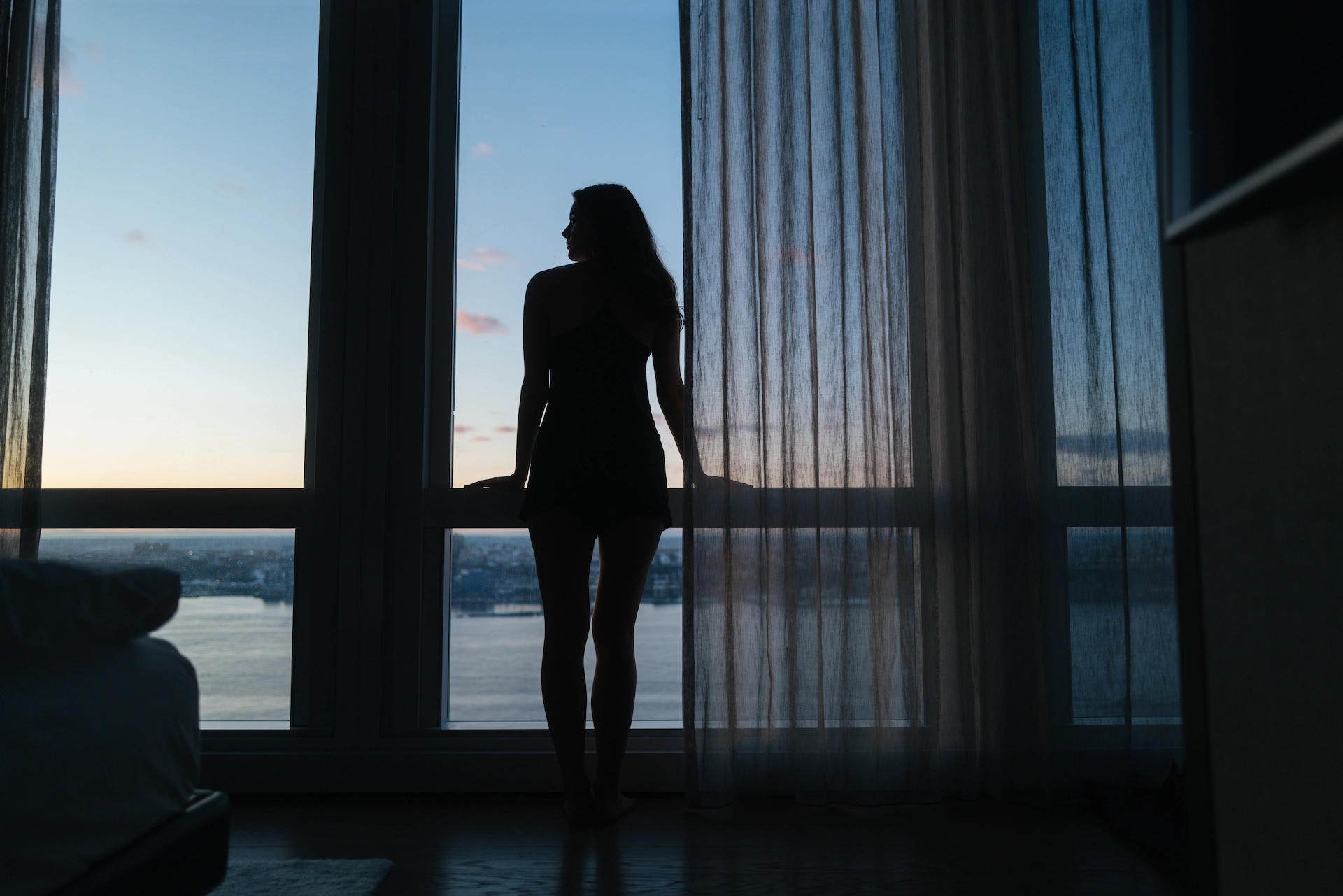 Woman gazing at the Hudson River during sunrise from a luxury room at Equinox Hotel New York.